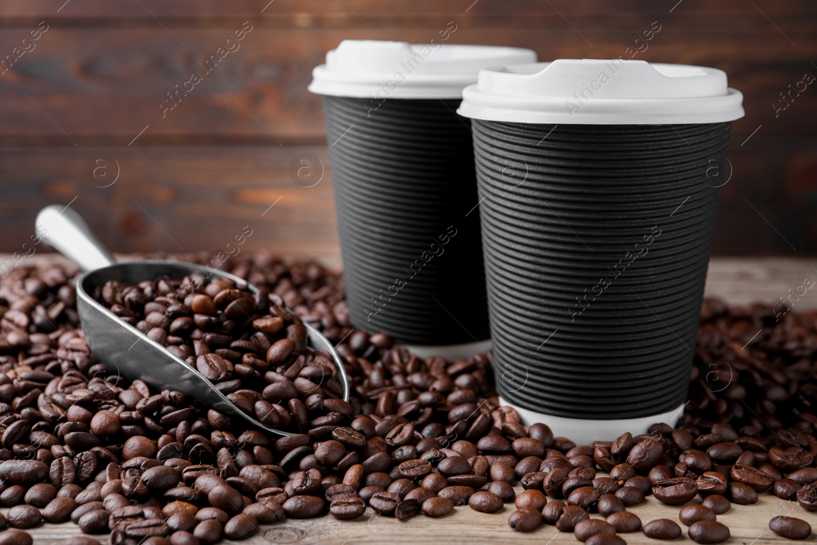 Photo of Coffee to go. Paper cups, roasted beans and scoop on table, closeup