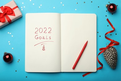 Photo of Open planner and Christmas decor on light blue background, flat lay. Planning for 2022 New Year