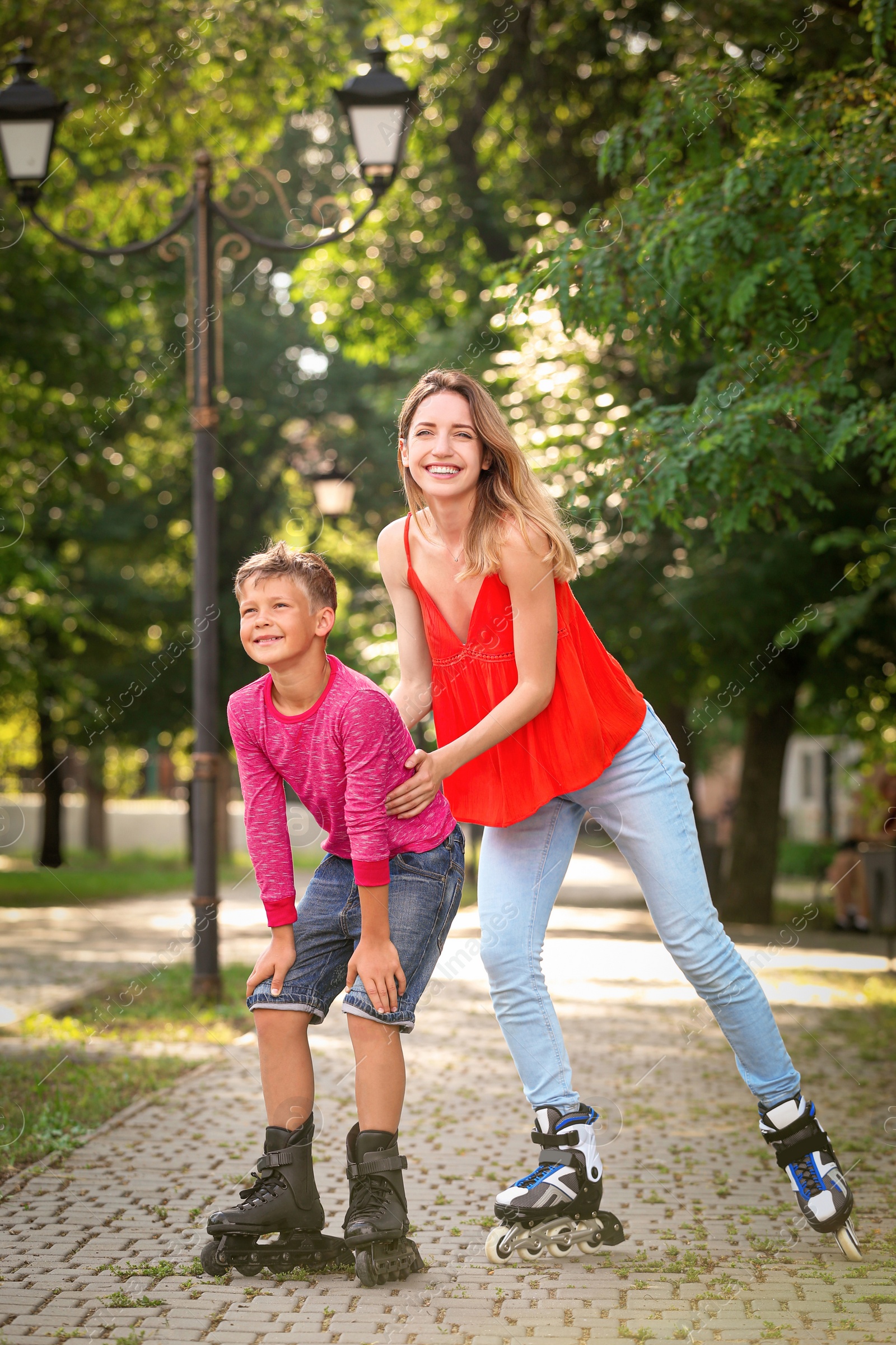 Photo of Mother and son roller skating in summer park