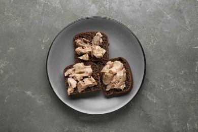 Photo of Tasty sandwiches with cod liver on grey table, top view