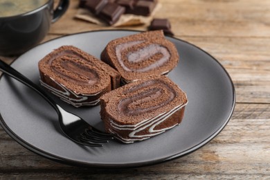 Tasty chocolate cake roll with cream on wooden table, closeup