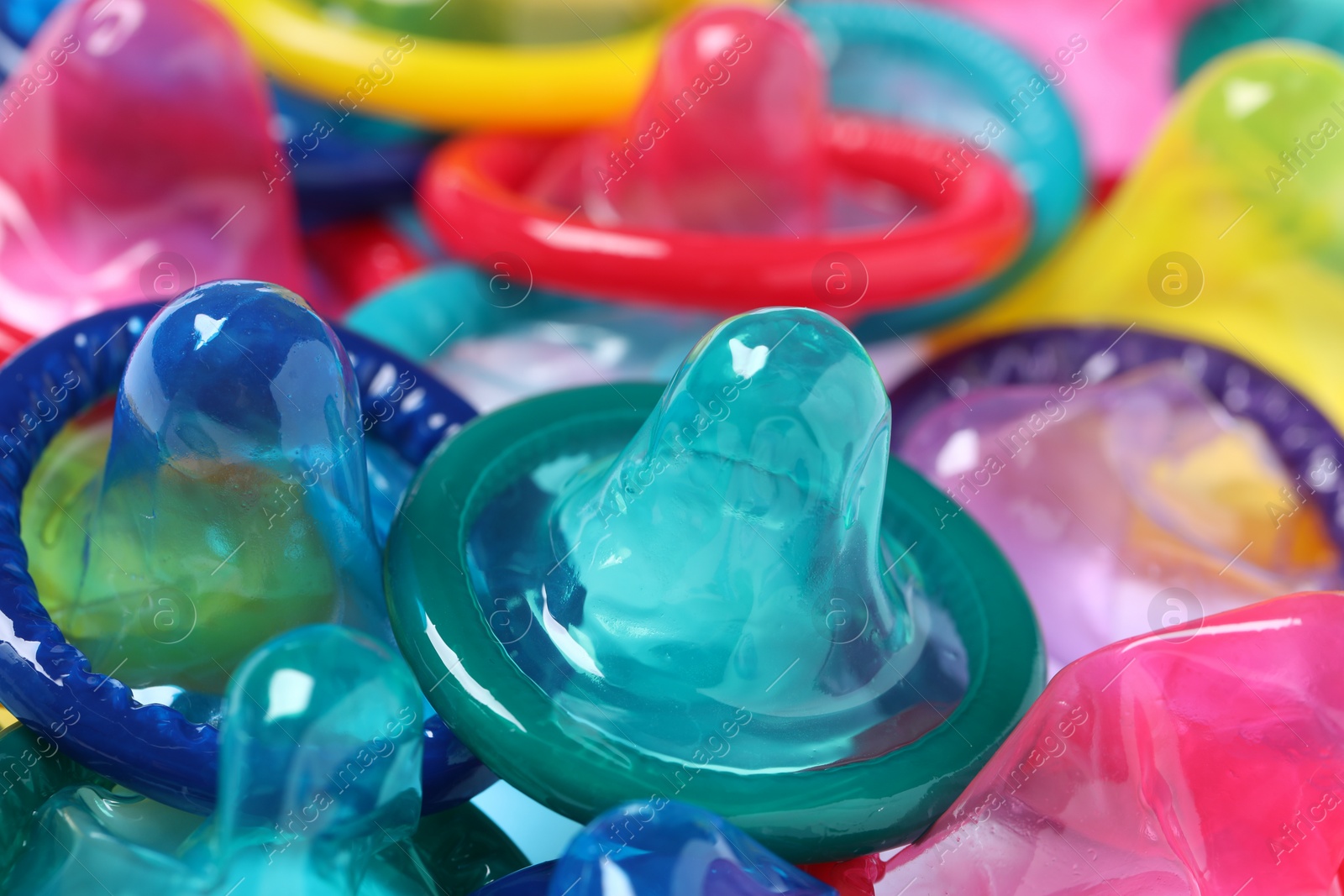 Photo of Colorful unpacked condoms as background, closeup view. Safe sex
