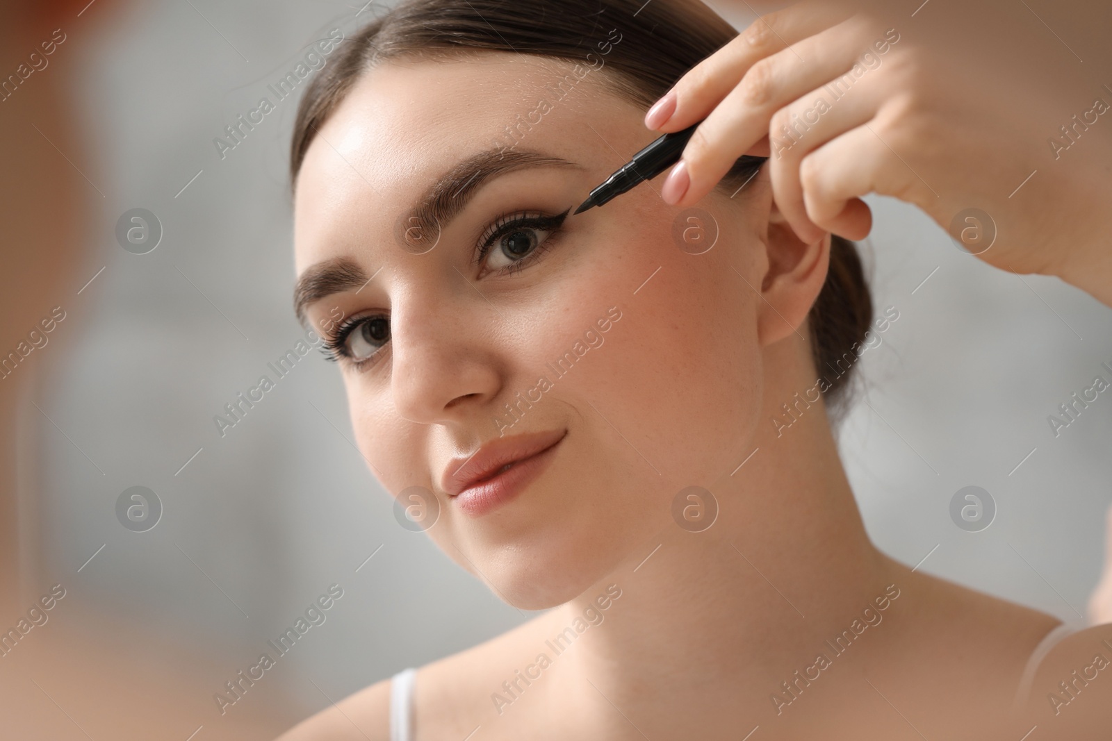 Photo of Makeup product. Woman applying black eyeliner indoors, closeup