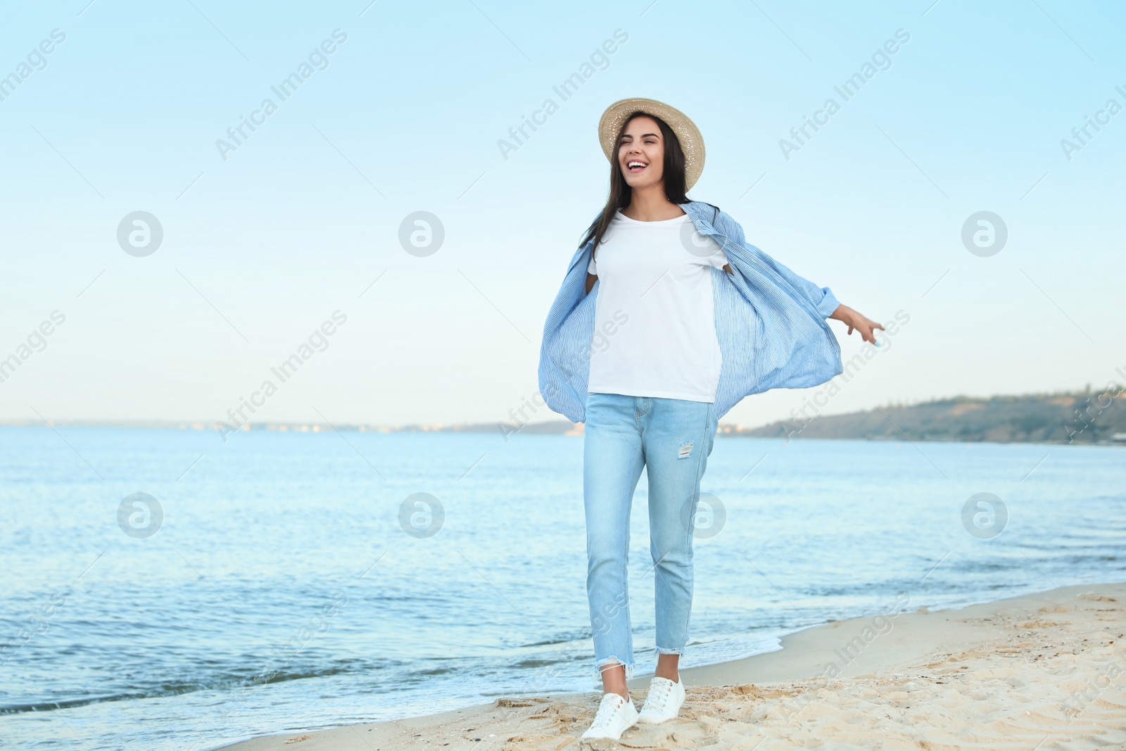 Photo of Beautiful young woman in casual outfit on beach