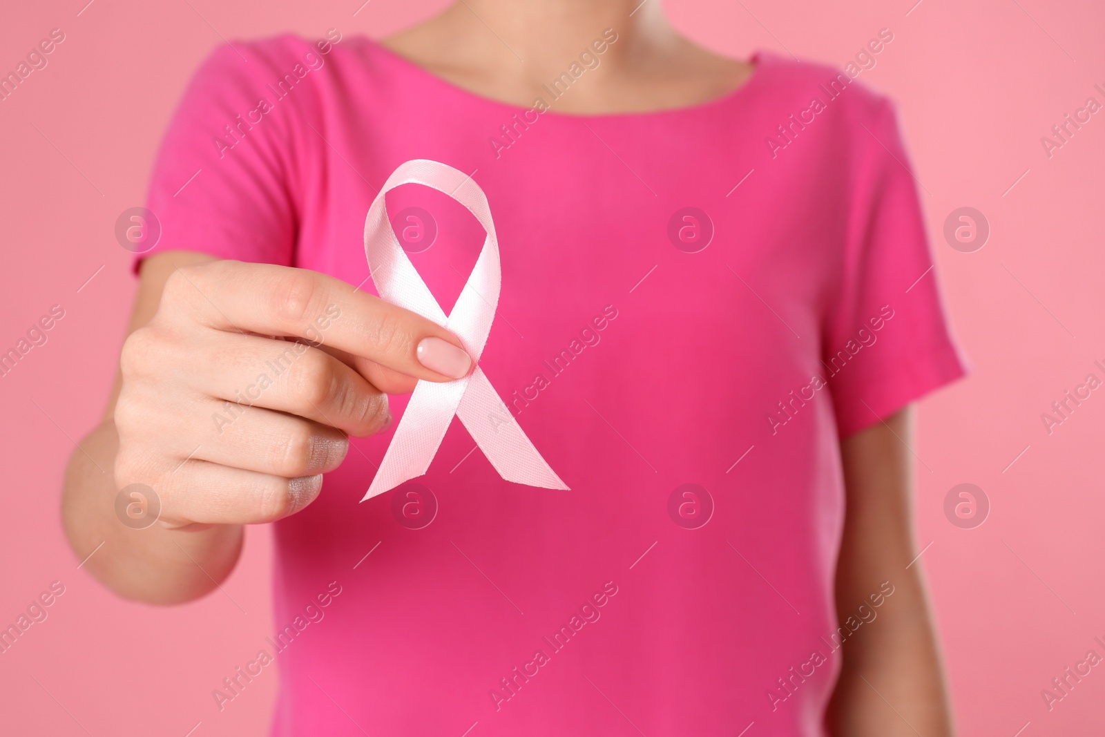 Photo of Woman holding pink ribbon on color background, closeup. Breast cancer awareness