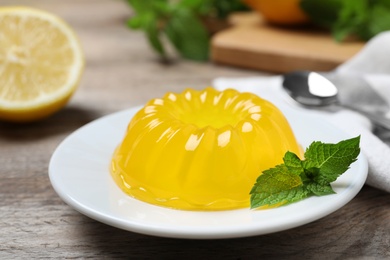 Photo of Delicious fresh yellow jelly with mint on wooden table