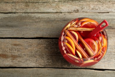 Photo of Glass bowl of aromatic punch drink on wooden table, top view. Space for text