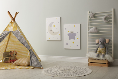 Photo of Stylish child's room interior with adorable paintings and play tent