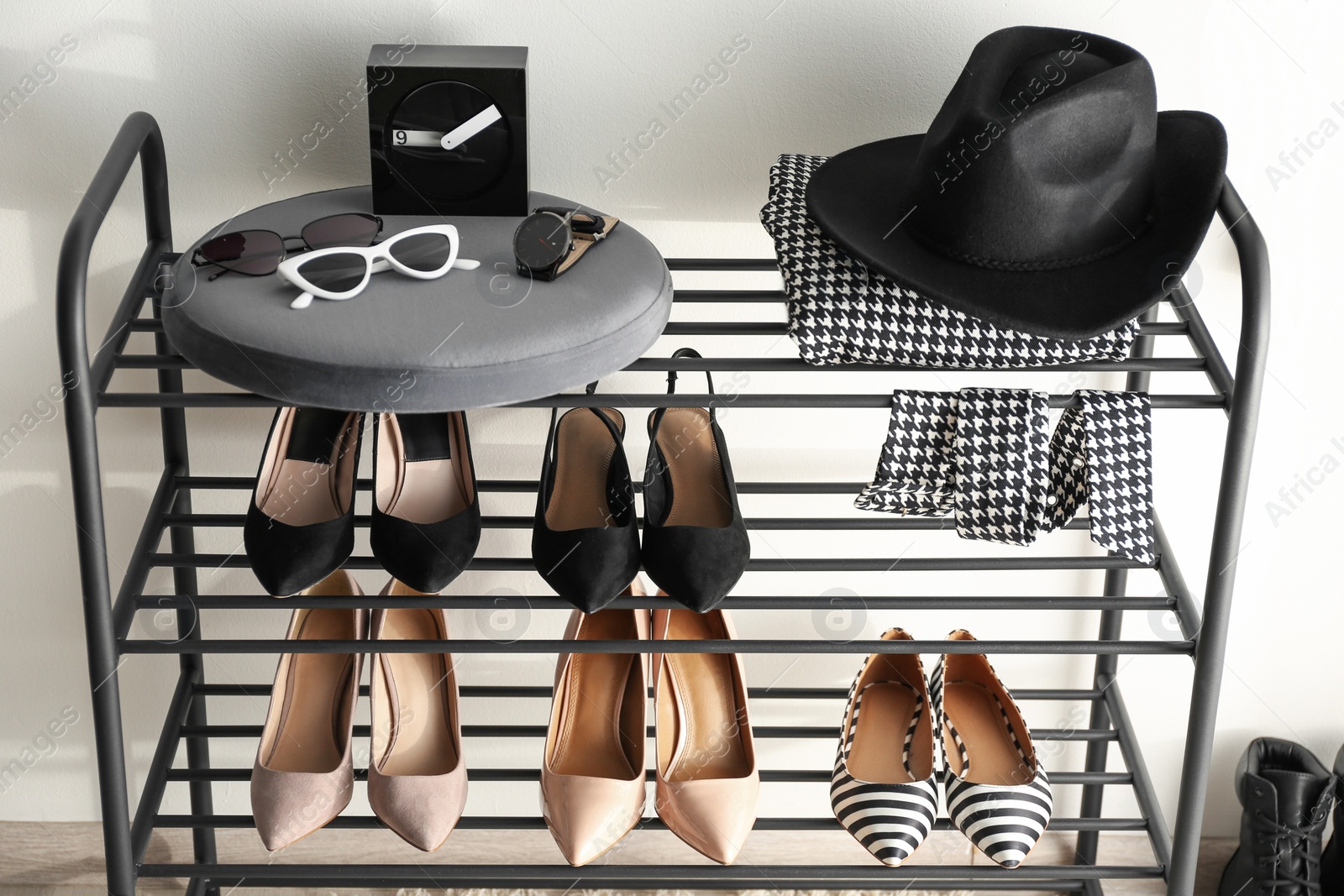 Photo of Black shelving unit with shoes and different accessories near white wall