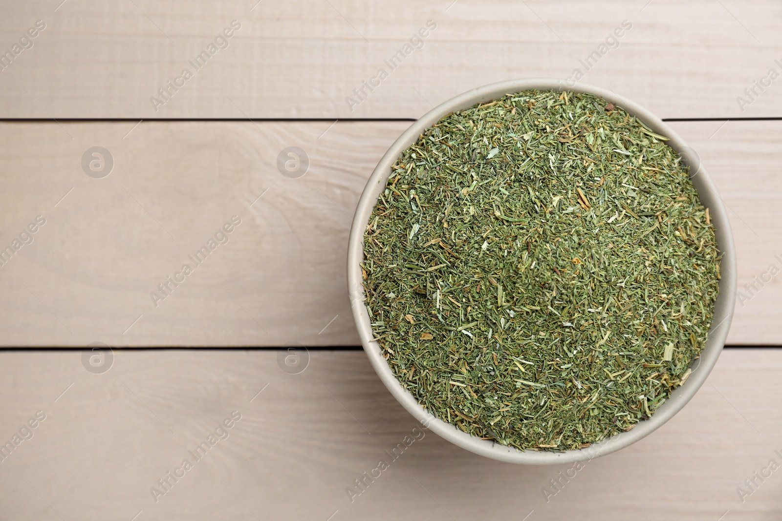 Photo of Dried dill in bowl on white wooden table, top view. Space for text