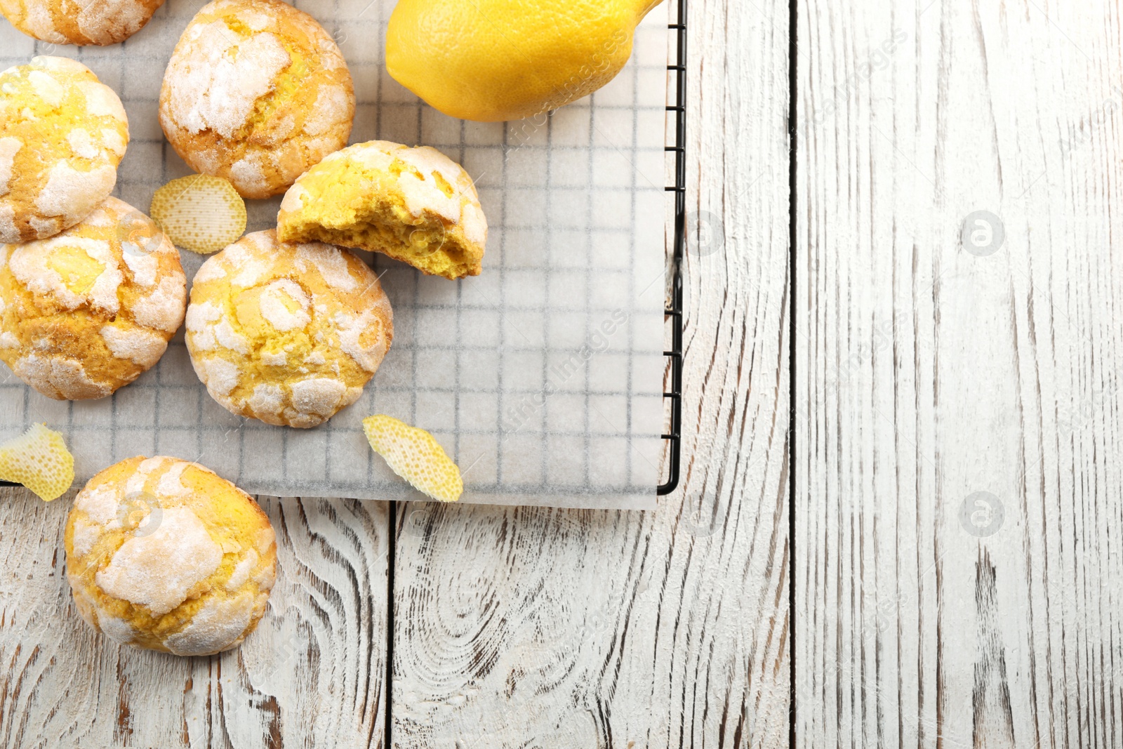 Photo of Cooling rack with delicious lemon cookies on white wooden table, flat lay. Space for text