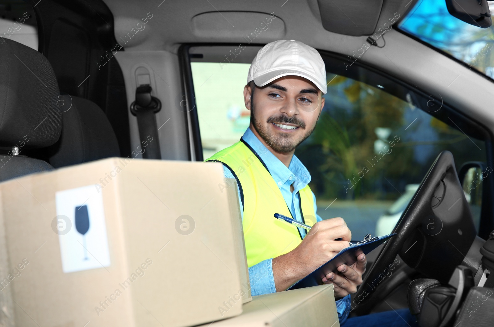 Photo of Young courier checking amount of parcels in delivery van