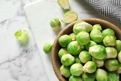 Bowl with fresh Brussels sprouts on marble table, top view. Space for text