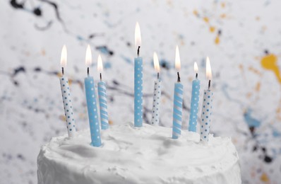 Photo of Delicious cake with cream and burning candles on color background, closeup