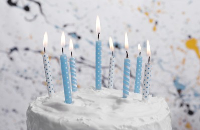 Delicious cake with cream and burning candles on color background, closeup