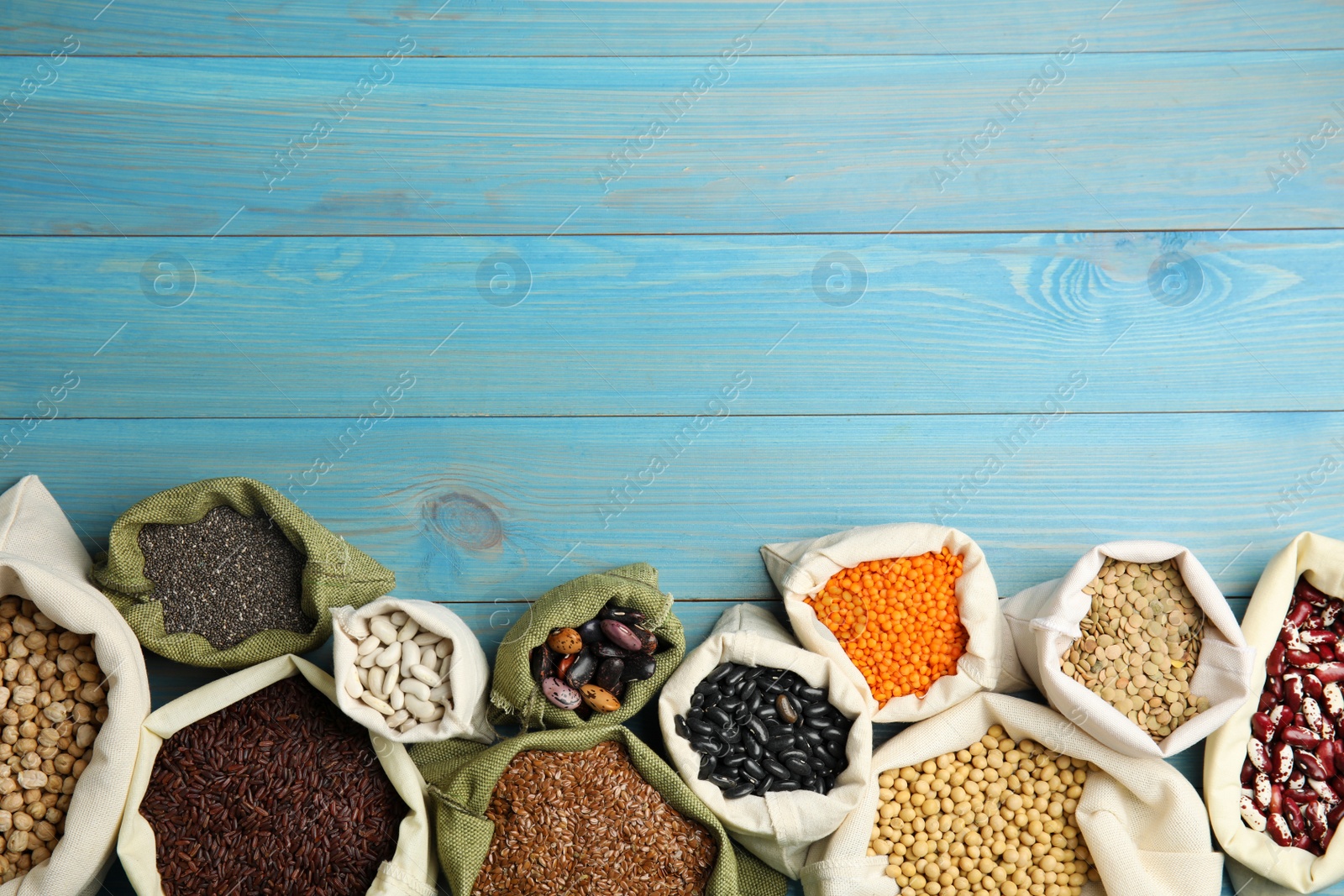 Photo of Different grains, seeds and space for text on light blue wooden table, flat lay. Veggie diet