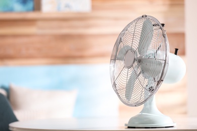 Photo of Modern electric fan on white table indoors. Space for text