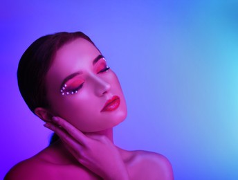 Image of Young woman with beautiful makeup posing in neon lights. Space for text
