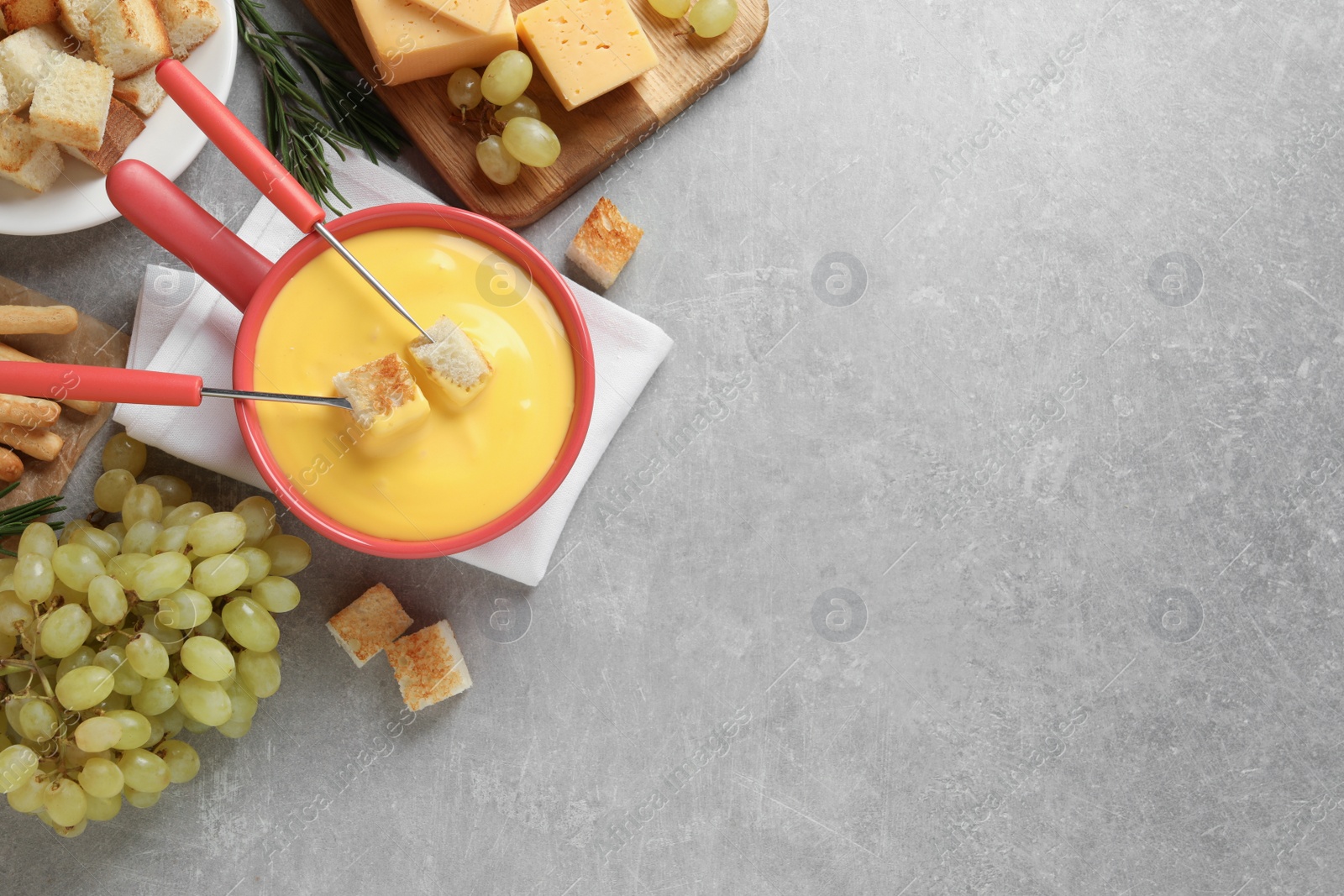 Photo of Flat lay composition with pot of tasty cheese fondue on grey table. Space for text