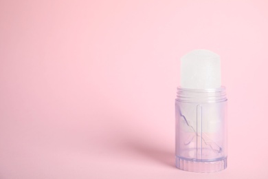 Natural crystal alum stick deodorant on pink background. Space for text