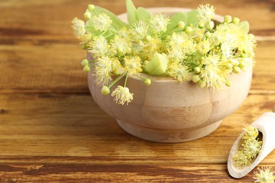 Fresh linden leaves and flowers on wooden table