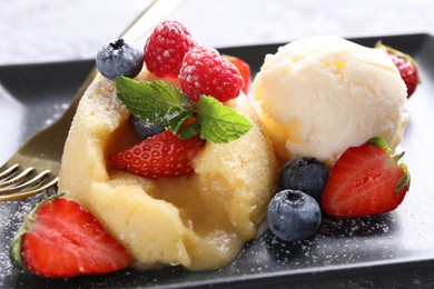 Tasty vanilla fondant with white chocolate, berries and ice cream on table, closeup