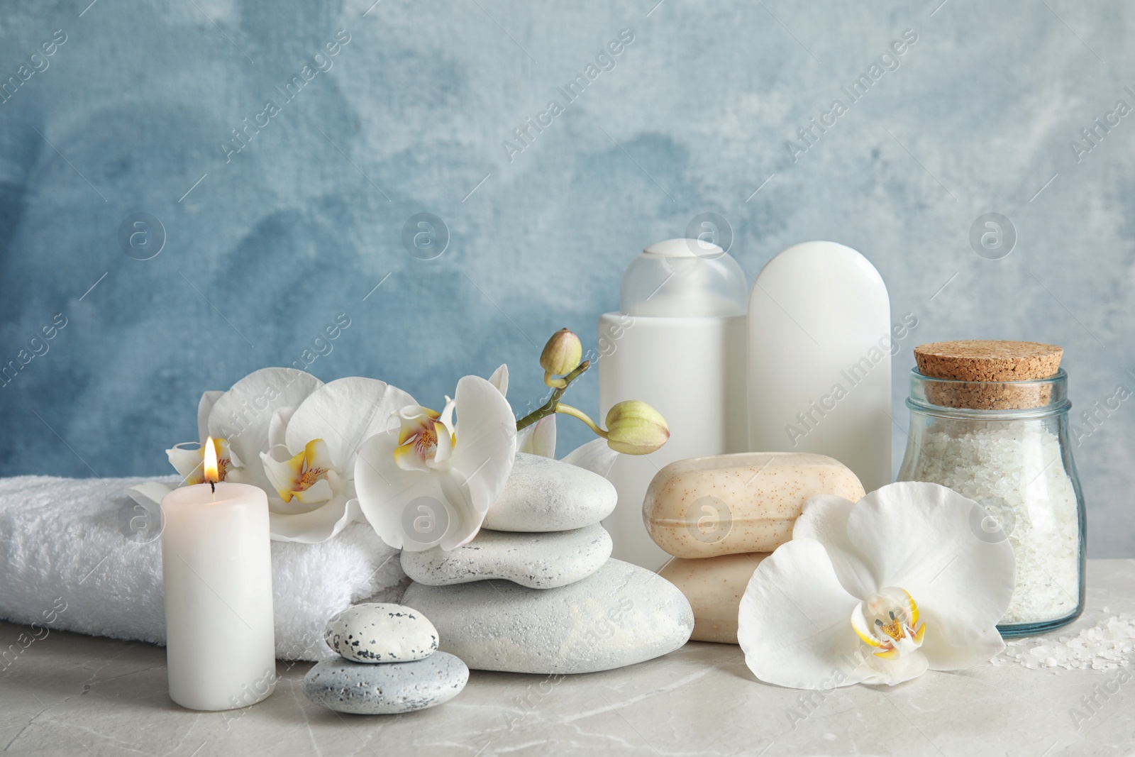 Photo of Beautiful composition with candle and spa stones on light table