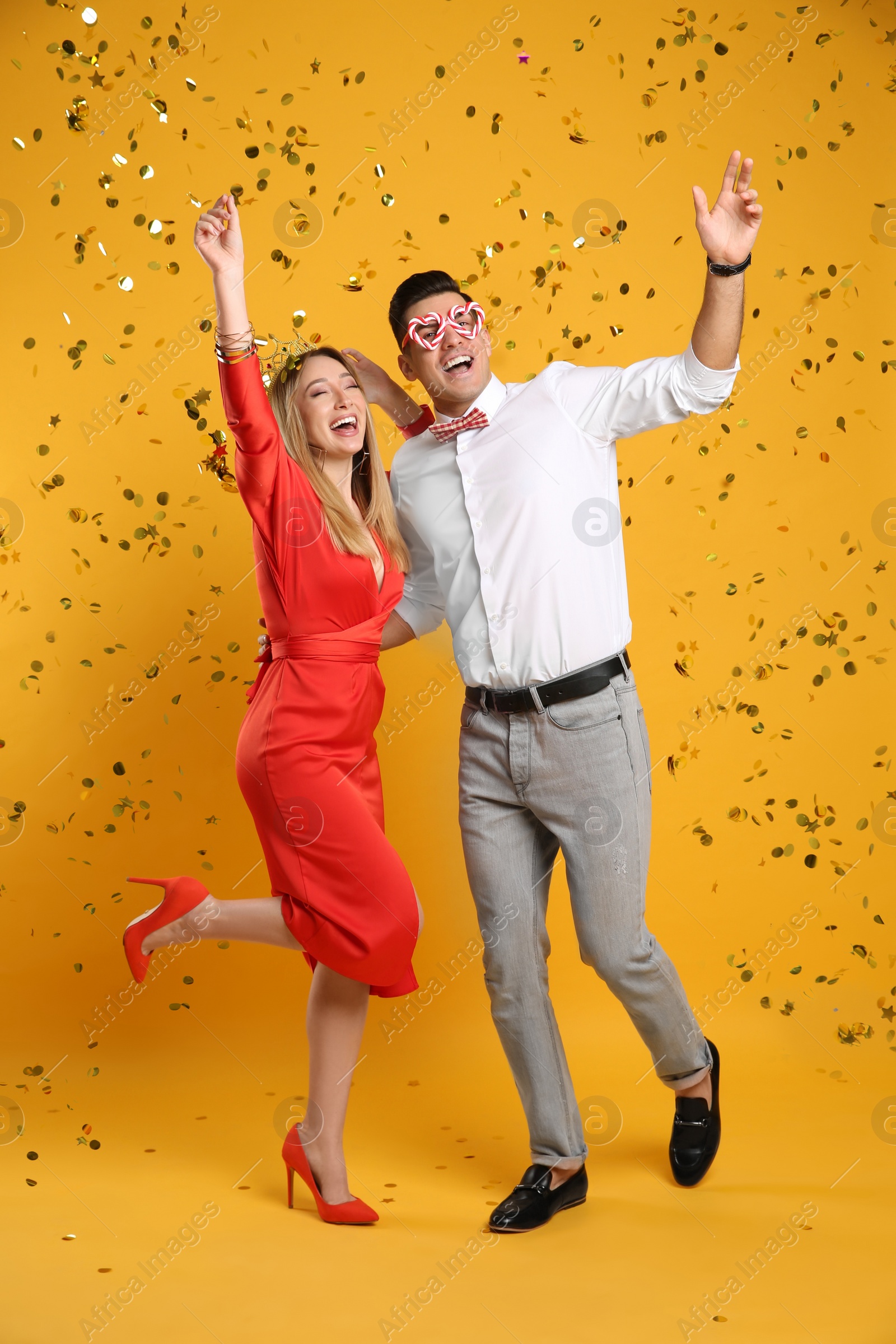 Photo of Happy couple and confetti on yellow background