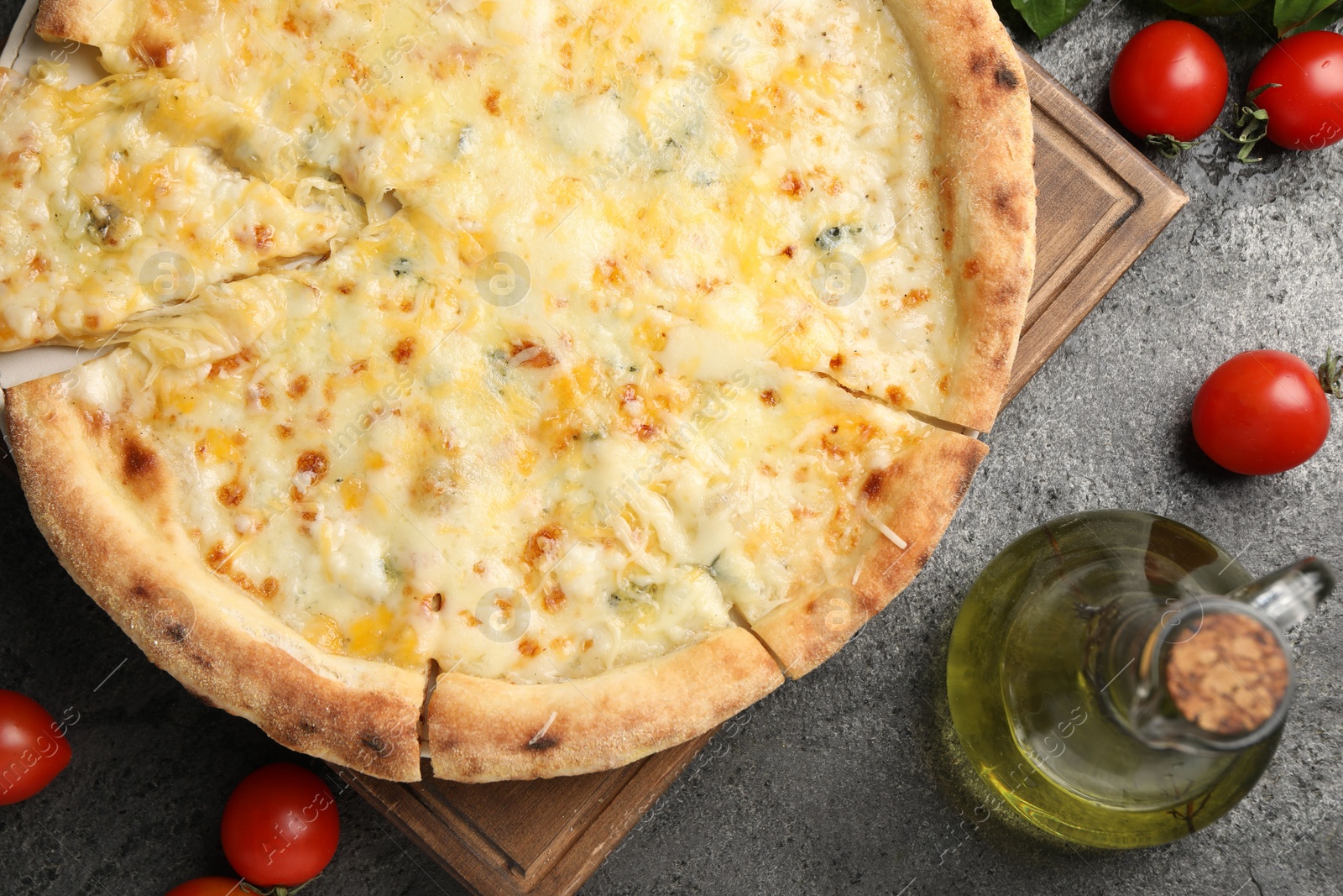 Photo of Delicious cheese pizza, oil and tomatoes on dark grey table, flat lay