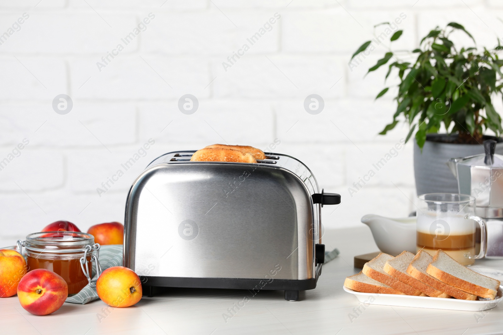 Photo of Toaster with roasted bread, coffee and nectarine jam on white wooden table, space for text. Tasty breakfast