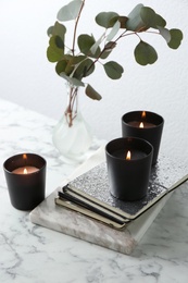 Composition with notebooks, burning candles and green branches on marble table