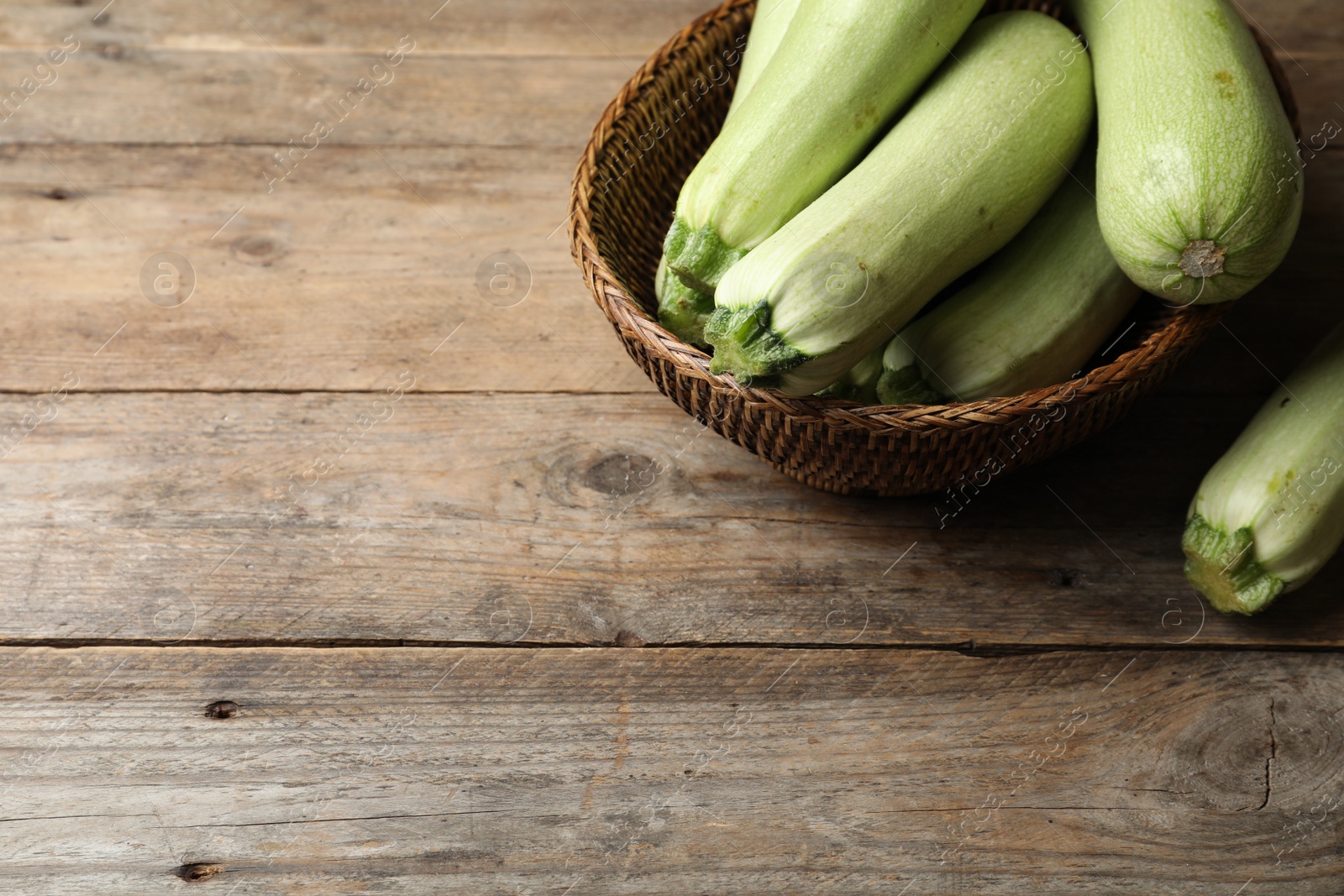 Photo of Ripe zucchinis on wooden table. Space for text