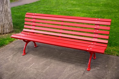 Photo of Beautiful red wooden bench near green grass in park