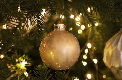 Photo of Beautiful baubles and fairy lights on Christmas tree, closeup