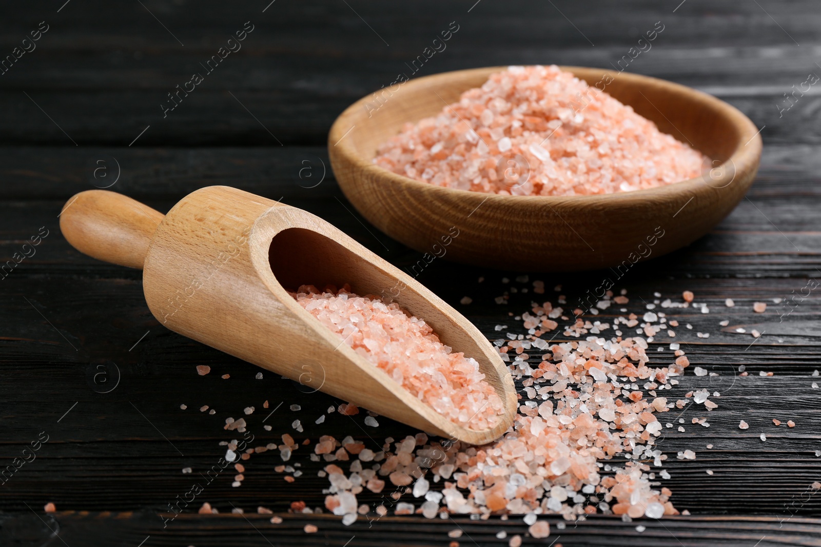 Photo of Pink himalayan salt in scoop and bowl on wooden table