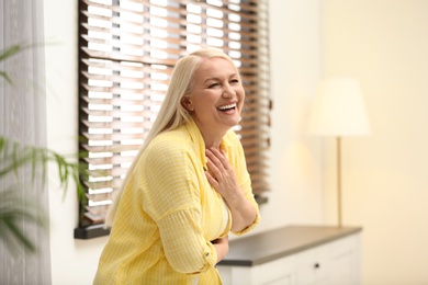 Portrait of happy mature woman near window indoors