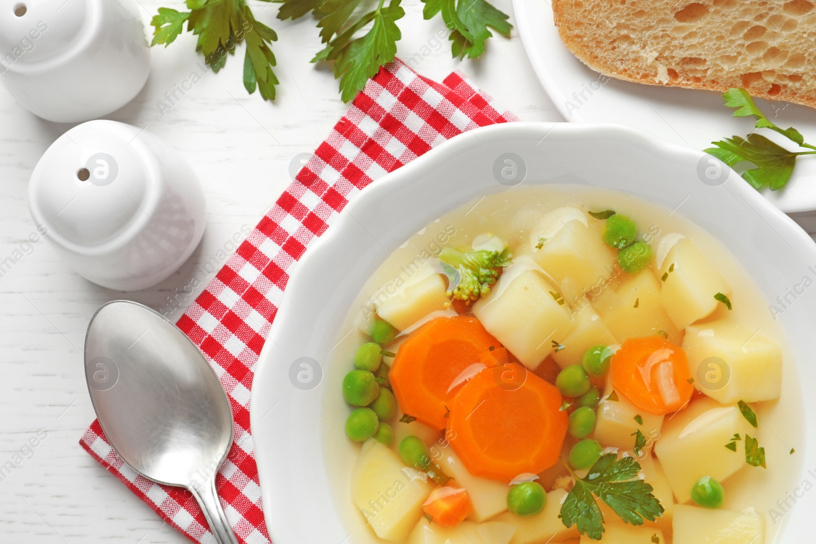 Photo of Bowl of fresh homemade vegetable soup served on white wooden table, flat lay