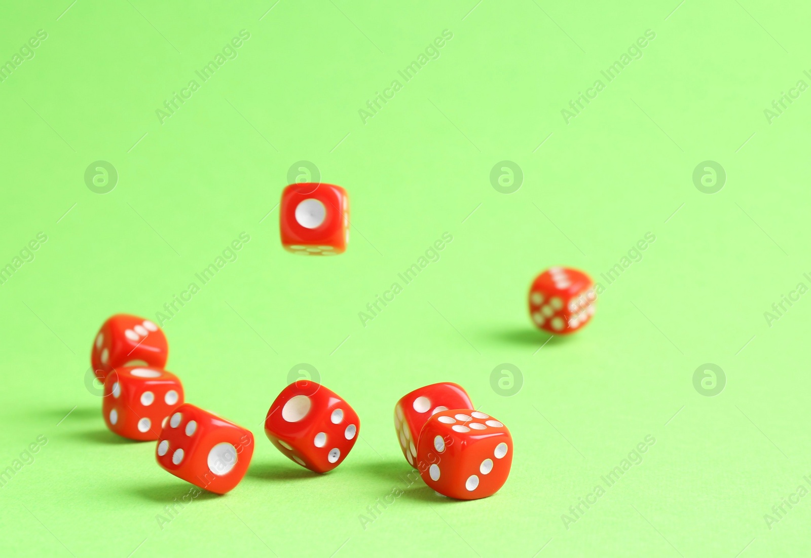 Photo of Many red game dices falling on green background. Space for text