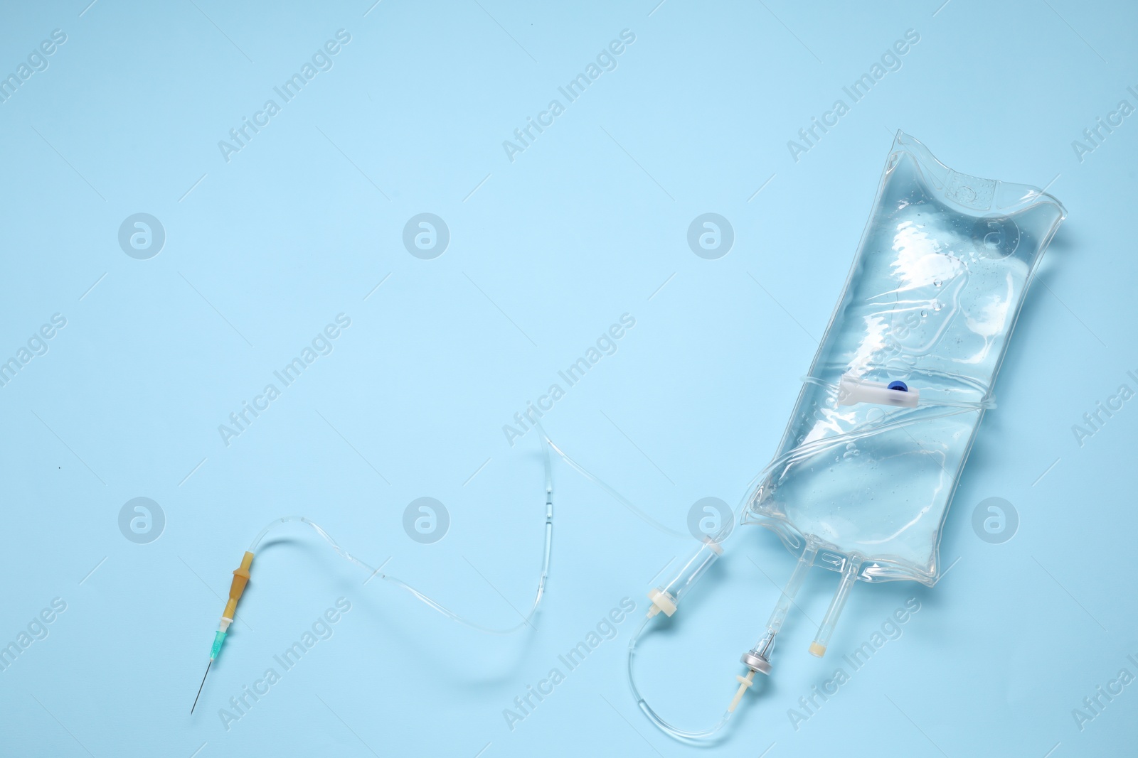 Photo of IV infusion set on light blue background, top view. Space for text