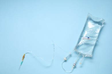 Photo of IV infusion set on light blue background, top view. Space for text