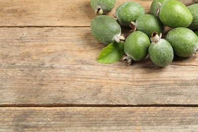 Fresh green feijoa fruits on wooden table, space for text