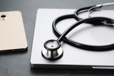 Photo of Modern electronic devices and stethoscope on black table, closeup