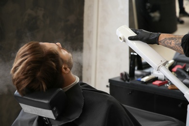 Photo of Hairdresser working with client at barbershop. Professional shaving service