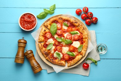 Photo of Delicious Margherita pizza and ingredients on light blue wooden table, top view