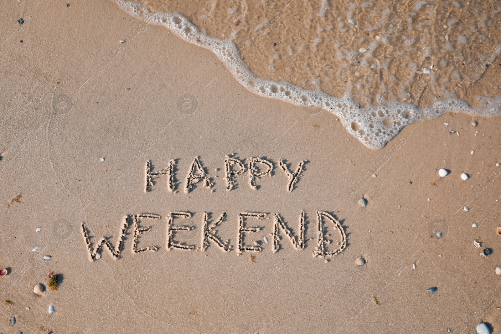 Photo of Phrase Happy weekend written on sand at beach, top view