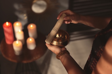 Photo of Healer using singing bowl in dark room, closeup