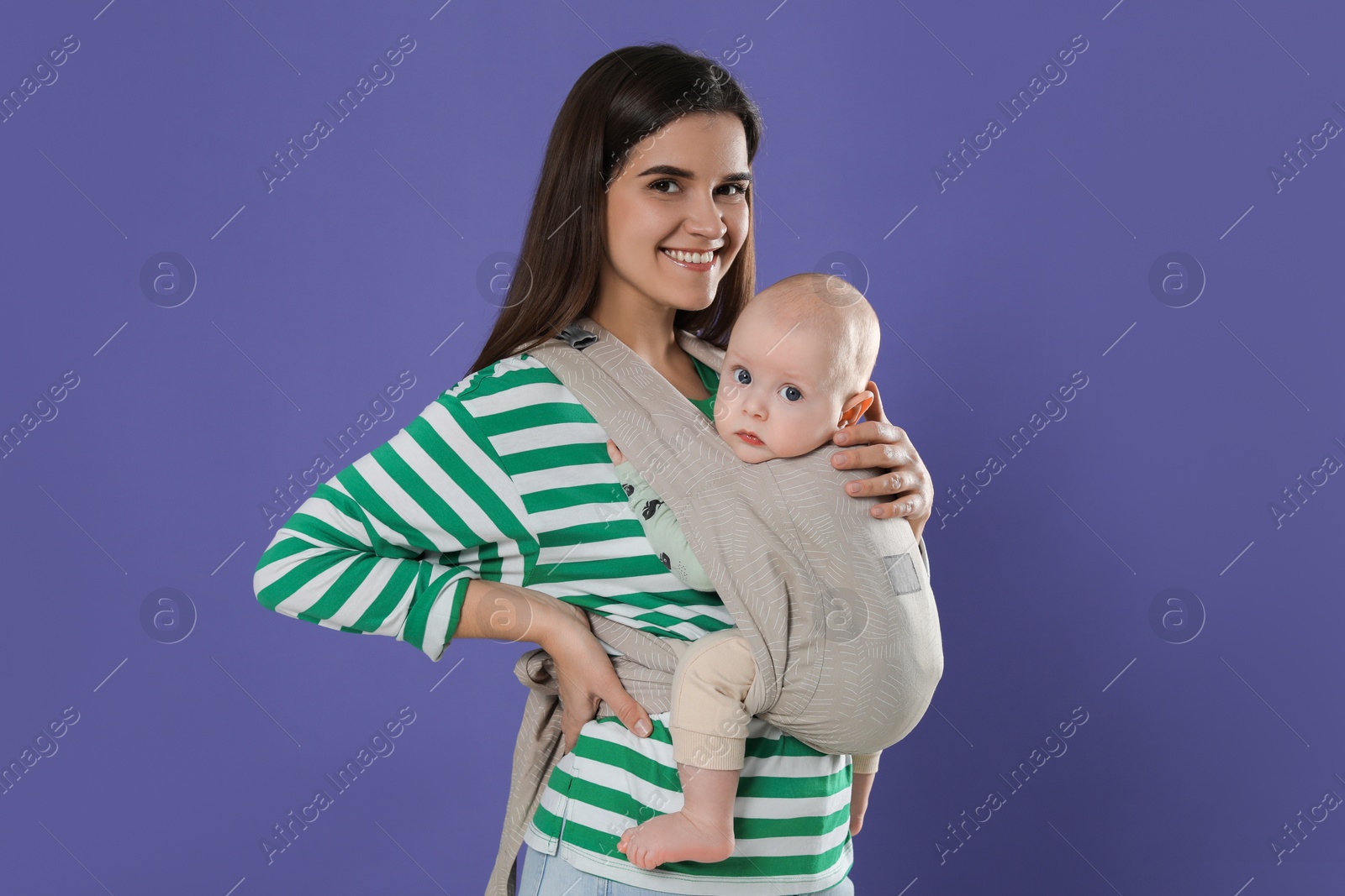 Photo of Mother holding her child in sling (baby carrier) on purple background