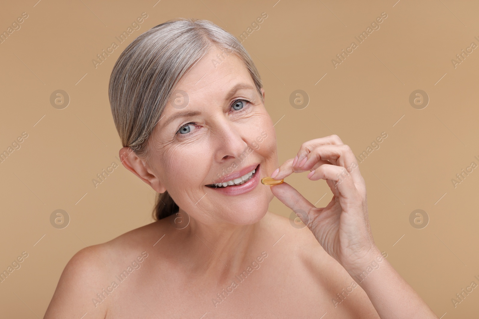 Photo of Beautiful woman with vitamin capsule on beige background