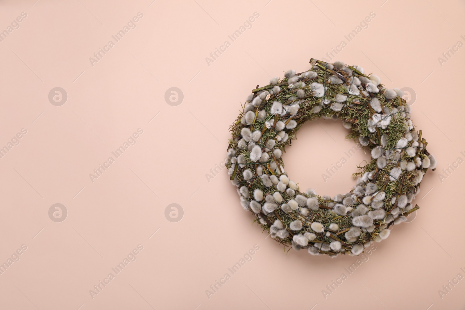 Photo of Wreath made of beautiful willow flowers on beige background, top view. Space for text