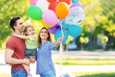 Photo of Happy family with colorful balloons in park on sunny day
